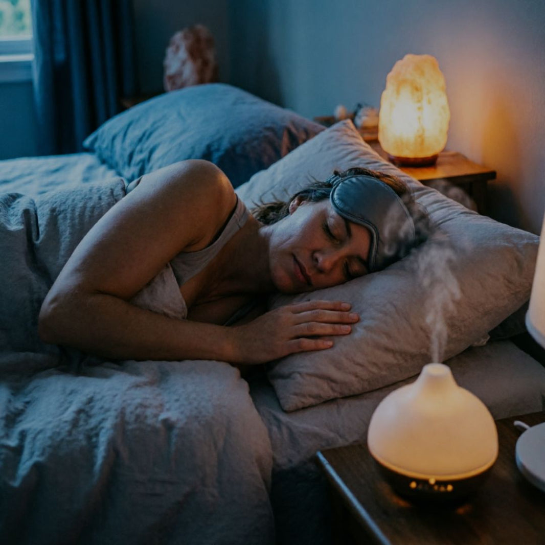 Woman sleeping in bed with a night light on, wearing an eye mask.